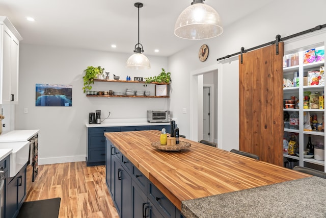 29 Hawks Nest Ln, Wells, ME 04090 - kitchen featuring butcher block countertops, light wood-style floors, a barn door, baseboards, and hanging light fixtures