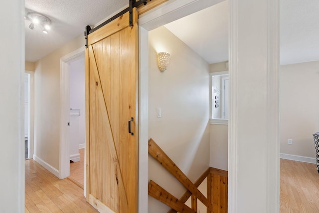 48 Woodside Dr, Kennebunk, ME 04043 - hall featuring a barn door, an upstairs landing, and light wood-style flooring