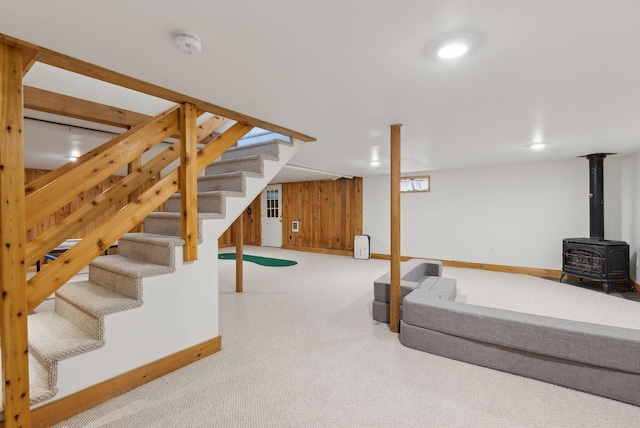 48 Woodside Dr, Kennebunk, ME 04043 - unfurnished living room with carpet flooring, baseboards, a wood stove, stairs, and wood walls