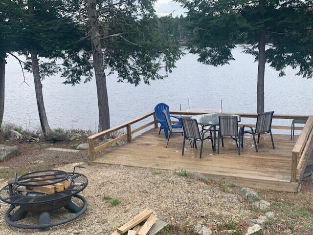 dock area featuring a fire pit, a deck with water view, and outdoor dining space