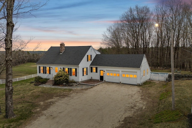 view of front facade featuring fence, a chimney, a shingled roof, an attached garage, and driveway