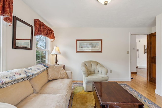 living room with baseboards, light wood finished floors, and a baseboard heating unit