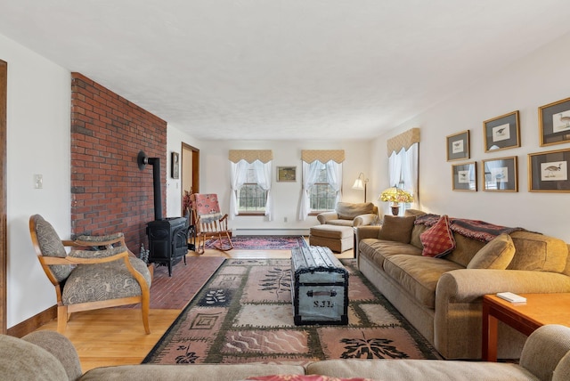 living room featuring baseboards, baseboard heating, a wood stove, and wood finished floors