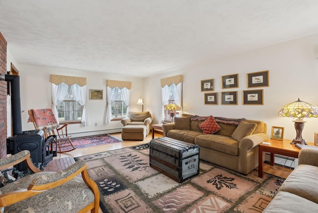 living area featuring a baseboard heating unit, wood finished floors, and a wood stove
