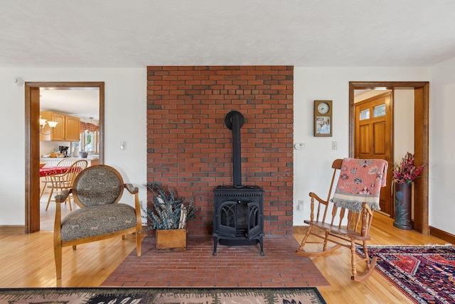 sitting room with light wood-style floors, baseboards, and a wood stove