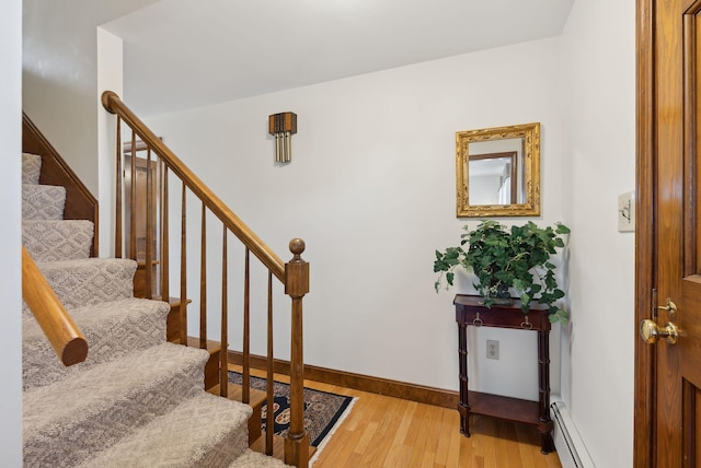 stairway with baseboard heating, baseboards, and wood finished floors