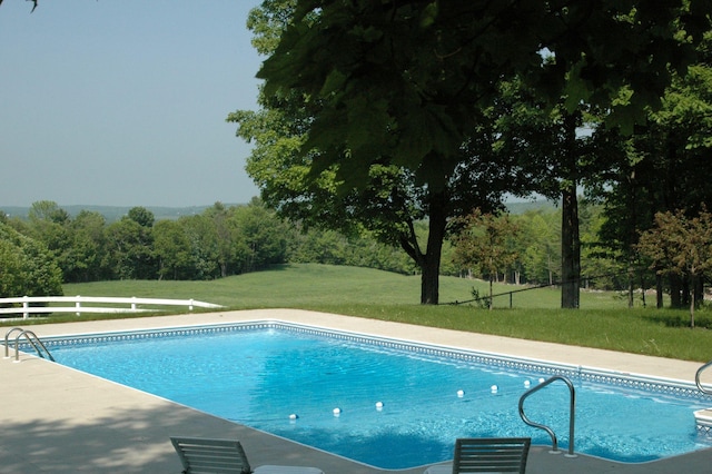pool featuring fence and a yard