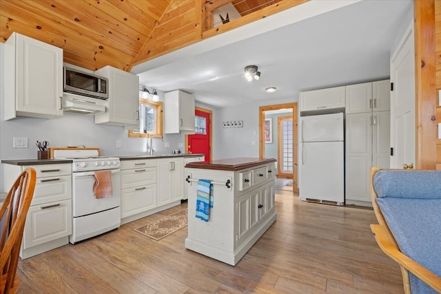 kitchen featuring dark countertops, exhaust hood, white appliances, and white cabinetry