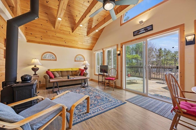 living area with a wood stove, beamed ceiling, ceiling fan, high vaulted ceiling, and wooden ceiling