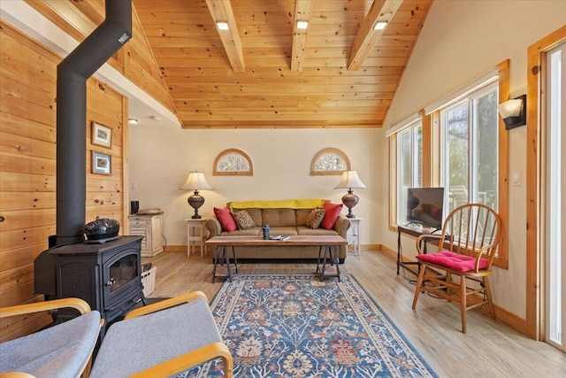 living area with a wood stove, wood finished floors, baseboards, vaulted ceiling with beams, and wood ceiling