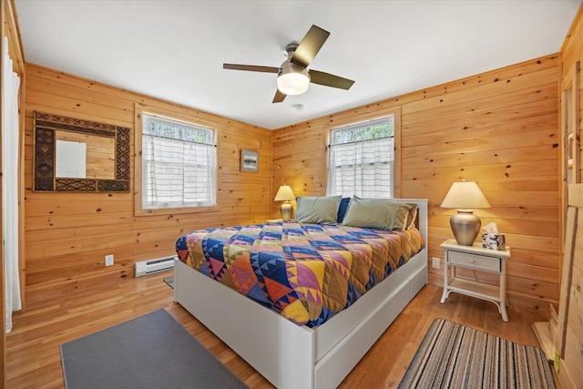 bedroom featuring wooden walls, ceiling fan, light wood finished floors, and a baseboard radiator