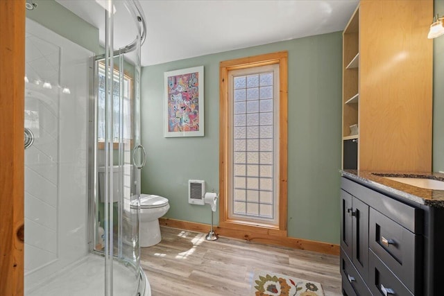 full bath featuring a stall shower, wood finished floors, baseboards, vanity, and toilet