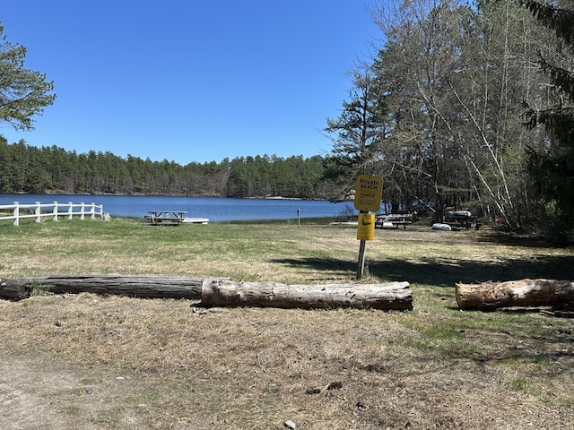 property view of water featuring fence and a wooded view
