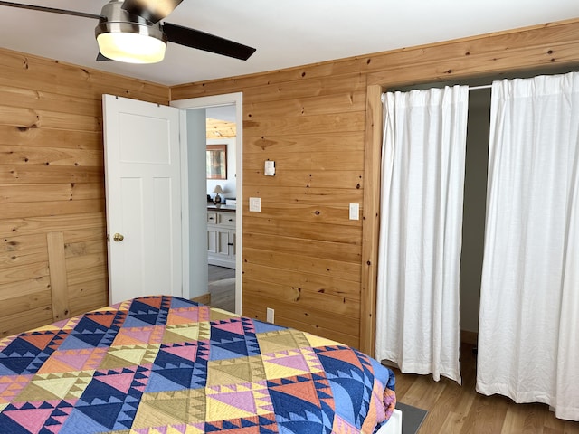 bedroom with a ceiling fan, wood walls, and wood finished floors