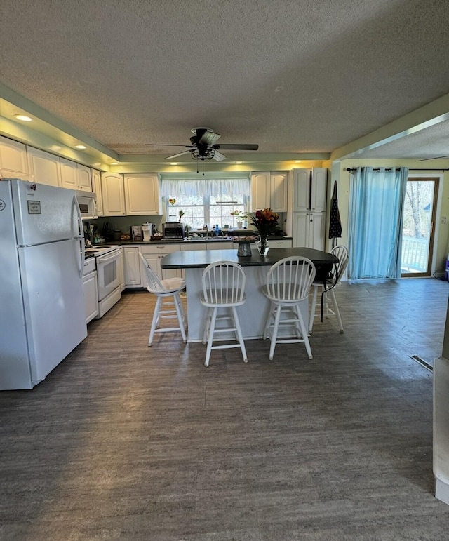 1002 River Rd, Orrington, ME 04474 - kitchen with a center island, dark countertops, a textured ceiling, and white appliances