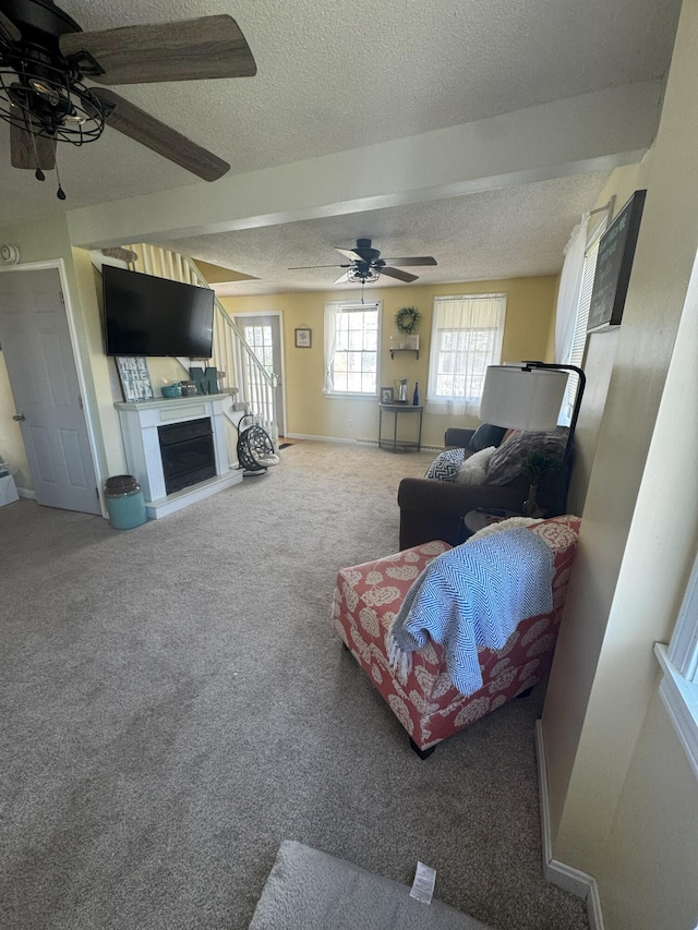 1002 River Rd, Orrington, ME 04474 - living area featuring carpet floors, a fireplace, baseboards, ceiling fan, and a textured ceiling