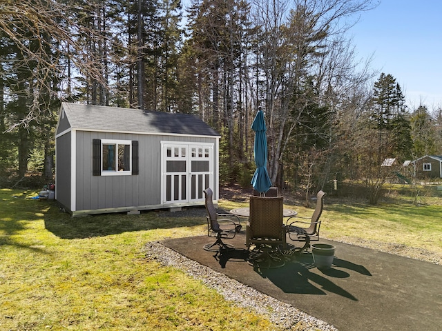 view of yard featuring a patio, a shed, and an outbuilding