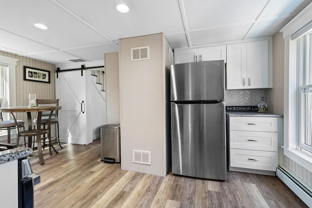 kitchen with freestanding refrigerator, visible vents, a barn door, and baseboard heating