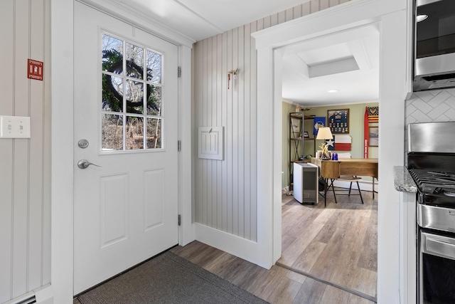 doorway featuring baseboards, ornamental molding, and wood finished floors