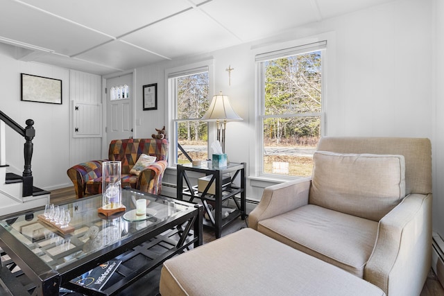 sitting room with stairs, baseboard heating, and wood finished floors