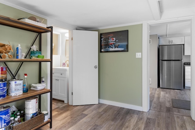 interior space featuring freestanding refrigerator, a sink, wood finished floors, and white cabinets