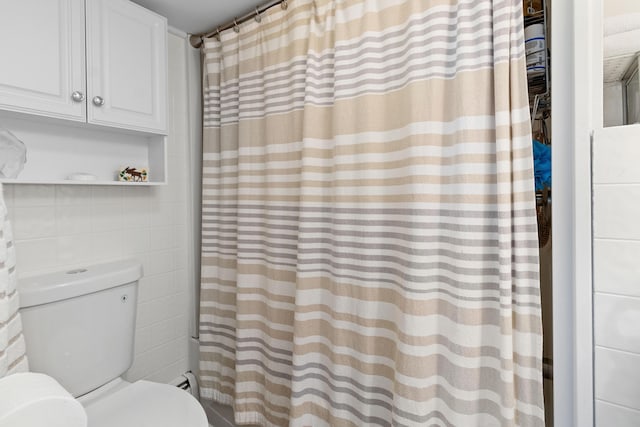 full bath with toilet, tile walls, and curtained shower