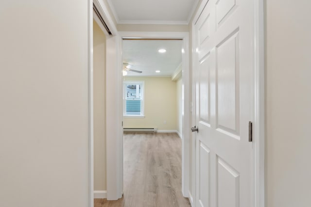 corridor featuring crown molding, baseboards, a baseboard heating unit, and light wood-style floors