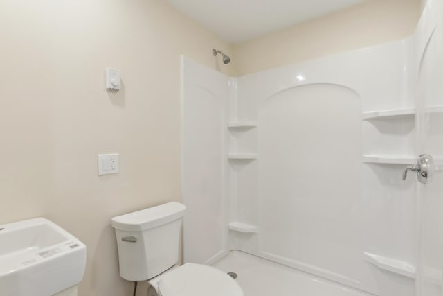 bathroom featuring a sink, walk in shower, and toilet