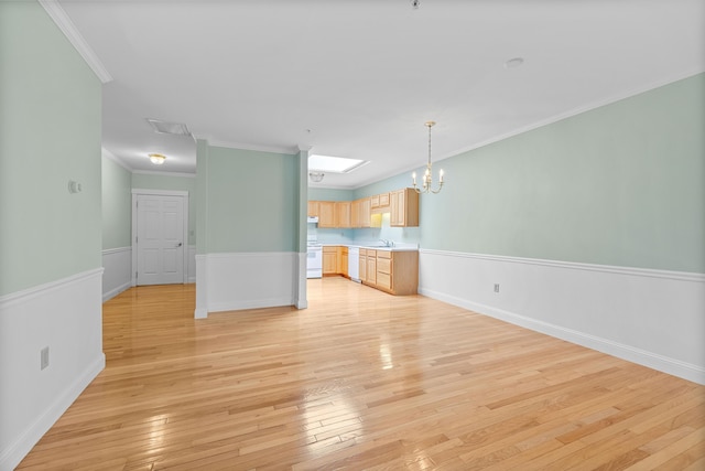 unfurnished living room featuring a sink, crown molding, a notable chandelier, and light wood-type flooring