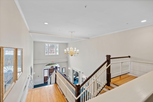 interior space with wood finished floors, ornamental molding, and a notable chandelier