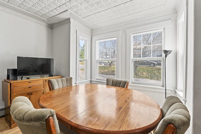 dining area with plenty of natural light, ornamental molding, light wood-style floors, and an ornate ceiling