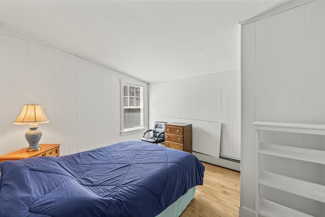 bedroom featuring vaulted ceiling, wood finished floors, and a baseboard radiator