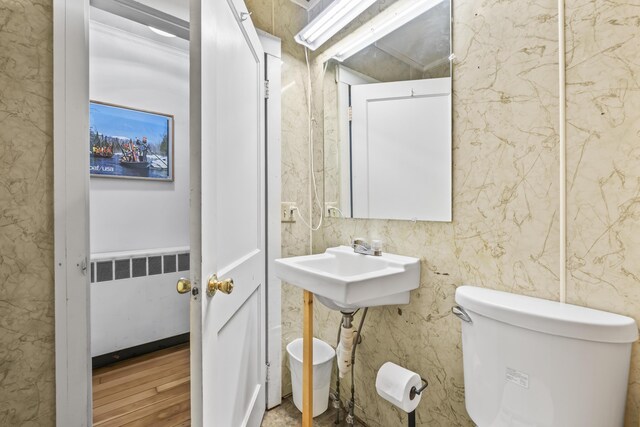 bathroom featuring toilet, radiator heating unit, and wood finished floors