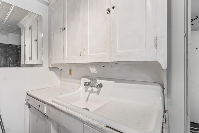 interior space featuring a sink, light countertops, and white cabinetry
