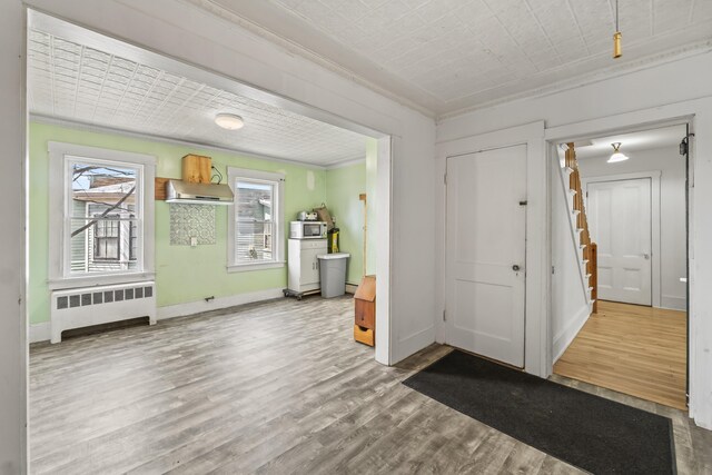 entrance foyer with baseboards, ornamental molding, wood finished floors, and radiator