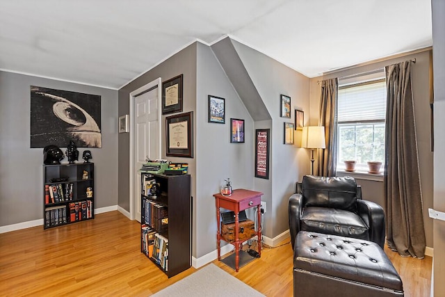 living area with baseboards, ornamental molding, and wood finished floors