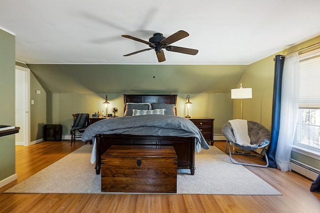 bedroom featuring a baseboard radiator, baseboard heating, vaulted ceiling, and wood finished floors