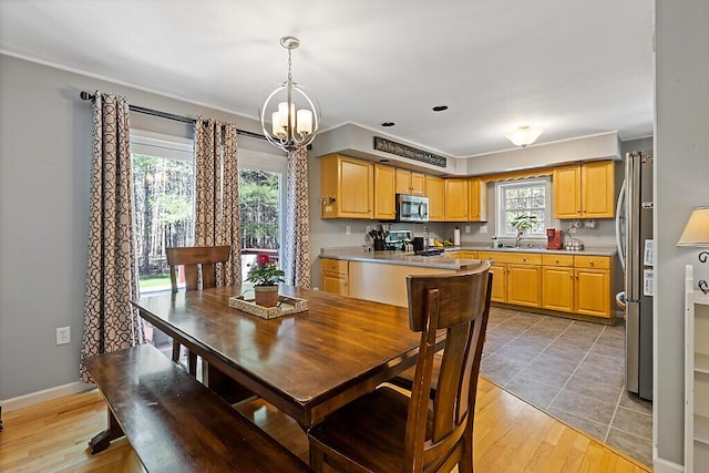 dining area featuring an inviting chandelier, light wood-style flooring, and baseboards