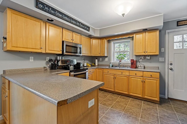 kitchen featuring a sink, appliances with stainless steel finishes, light brown cabinets, and a peninsula