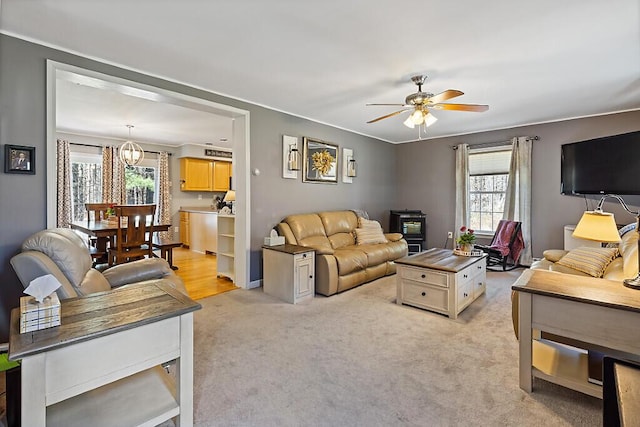 living room with light carpet, ceiling fan with notable chandelier, and a wealth of natural light