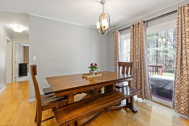 dining room featuring crown molding, light wood-style flooring, and a chandelier