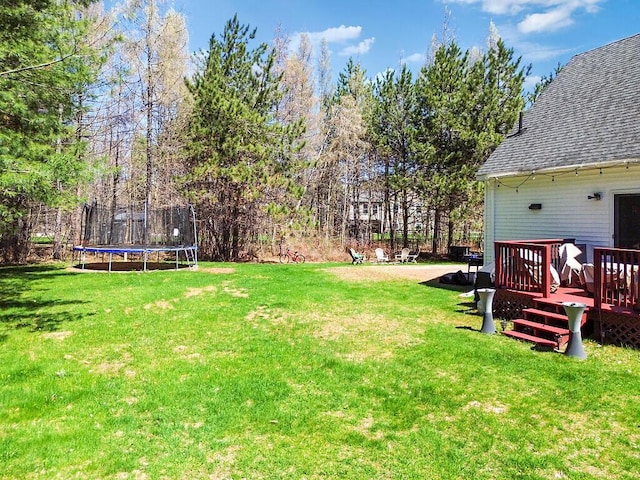 view of yard featuring a wooden deck and a trampoline