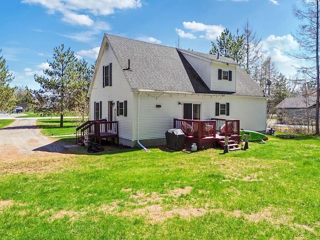 rear view of house with roof with shingles, a yard, and a deck