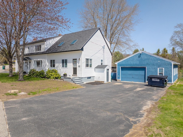 view of front of house featuring a storage unit, a shingled roof, a detached garage, a chimney, and an outdoor structure