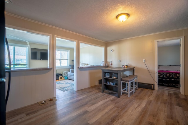 dining area with crown molding, a textured ceiling, and wood finished floors