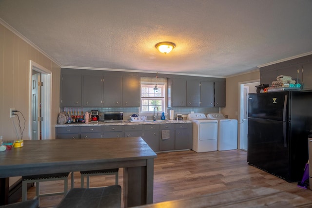 kitchen featuring a sink, separate washer and dryer, freestanding refrigerator, gray cabinetry, and ornamental molding