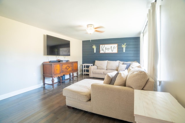 living room featuring baseboards, ceiling fan, and dark wood-type flooring