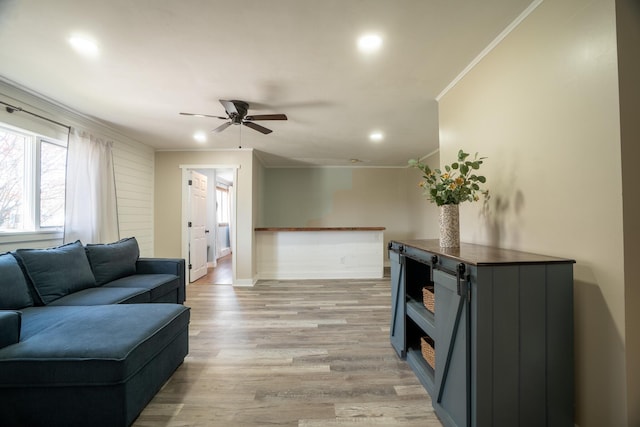 living area featuring ornamental molding, baseboards, ceiling fan, light wood-type flooring, and recessed lighting