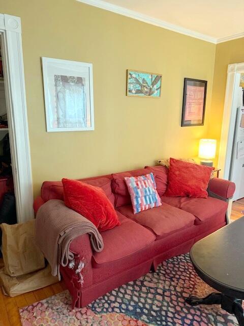 living area with ornamental molding and wood finished floors