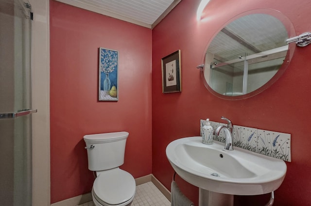bathroom with baseboards, a sink, an enclosed shower, and toilet